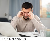 Man rubs tired eyes with his hands after a long work at laptop at home. Стоковое фото, фотограф Яков Филимонов / Фотобанк Лори