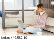Smiling young woman with headphones and laptop on the sofa at home.. Smiling young woman with headphones and laptop on the sofa. Стоковое фото, агентство Ingram Publishing / Фотобанк Лори