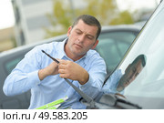 man inspecting the cars wipers. Стоковое фото, агентство Ingram Publishing / Фотобанк Лори