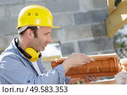 mature builder holding a new clay roof tile. Стоковое фото, агентство Ingram Publishing / Фотобанк Лори