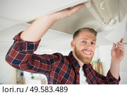 electrician man worker in uniform installing ceiling fluorescent lamp. Стоковое фото, агентство Ingram Publishing / Фотобанк Лори