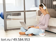 Smiling young woman with headphones and laptop on the sofa at home.. Smiling young woman with headphones and laptop on the sofa. Стоковое фото, агентство Ingram Publishing / Фотобанк Лори