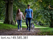 Young couple walking their pet dog along path in the park. Стоковое фото, агентство Ingram Publishing / Фотобанк Лори