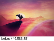 Wild pegasus silhouette on a cliff edge against a pink paradise sunset. Magical background, surreal creature as unicorn with wings, over the rainbow. Freedom and adventure concept, secret dreamland. Стоковое фото, агентство Ingram Publishing / Фотобанк Лори