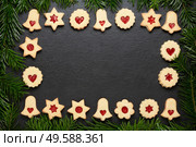 Homemade christmas linzer cookies with raspberry jam on slate table with pine branches. christmas cookies chocolate stars with raspberry crunches on slate table. Стоковое фото, агентство Ingram Publishing / Фотобанк Лори