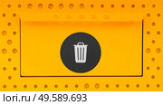 Yellow trash can close-up with a black sticker on the lit. Garbage bin opeing wit ha closed lit on a metal surface with an icon. Стоковое фото, агентство Ingram Publishing / Фотобанк Лори