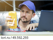 tradesman in roof space doing testing with voltmeter and laptop. Стоковое фото, агентство Ingram Publishing / Фотобанк Лори