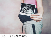 Woman holding the ultrasound of her baby. Стоковое фото, агентство Ingram Publishing / Фотобанк Лори
