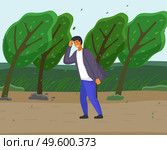Guy in jeans and shirt overcomes strong gusts of wind, protecting face with hand. Green trees are sloping from the wind, storm. Countryside, country road, summer or spring time. Storm before the rain. Guy walking along country road, strong gusts of wind will overcome, storm before summer rain. Стоковая иллюстрация, агентство Ingram Publishing / Фотобанк Лори