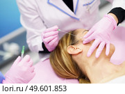 Doctor injecting PDO suture treatment threads into the face of a middle-aged woman.. Doctor injecting PDO suture treatment threads into the face of a woman. Стоковое фото, агентство Ingram Publishing / Фотобанк Лори