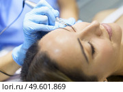 Permanent make-up for eyelashes of beautiful woman in a beauty salon. Close-up of beautician doing tattooing eyelashes. Micropigmentation treatment.. Permanent make-up for eyelashes of beautiful woman in a beauty salon. Micropigmentation treatment. Стоковое фото, агентство Ingram Publishing / Фотобанк Лори