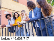 Multi-ethnic group of friends gathered in the street leaning on a railing. Young people having fun together.. Multi-ethnic group of friends gathered in the street leaning on a railing. Стоковое фото, агентство Ingram Publishing / Фотобанк Лори