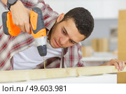 man drilling wood with cordless drill on the table. Стоковое фото, агентство Ingram Publishing / Фотобанк Лори