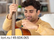 young male repairman repairing guitar. Стоковое фото, агентство Ingram Publishing / Фотобанк Лори