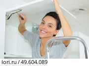 portrait of woman installing cupboard door. Стоковое фото, агентство Ingram Publishing / Фотобанк Лори