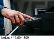 Person uses a multifunction printer to operate photocopying or scanning functions in an office setting during daylight hours. Стоковое фото, фотограф Сергей Толмачёв / Фотобанк Лори