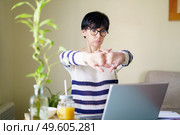 Woman teleworking from home with her laptop taking a stretch break.. Middle-aged woman teleworking taking a stretch break. Стоковое фото, агентство Ingram Publishing / Фотобанк Лори