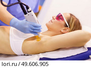 Woman receiving underarm laser hair removal at a beauty center. Laser depilation treatment in an aesthetic clinic.. Woman receiving underarm laser hair removal at a beauty center. Стоковое фото, агентство Ingram Publishing / Фотобанк Лори