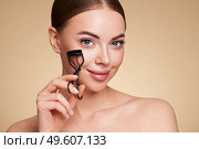 Close up of a beautiful young woman curling her eyelashes. Eyelash extensions. Стоковое фото, агентство Ingram Publishing / Фотобанк Лори