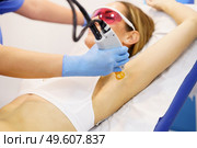Woman receiving underarm laser hair removal at a beauty center. Laser depilation treatment in an aesthetic clinic.. Woman receiving underarm laser hair removal at a beauty center. Стоковое фото, агентство Ingram Publishing / Фотобанк Лори