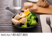 Ppieces of fried chicken breast with boiled broccoli and poached egg in cast iron portioned skillet. Стоковое фото, фотограф Татьяна Яцевич / Фотобанк Лори