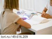 Manicured nails in UV lamp. Small nail art and manicure business. Hands of woman in a wellnes salon. Manicured nails in UV lamp. Small nail art and manicure business. Стоковое фото, агентство Ingram Publishing / Фотобанк Лори