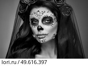 Portrait of a woman with sugar skull makeup over black background. Halloween costume and make-up. Portrait of Calavera Catrina. Стоковое фото, агентство Ingram Publishing / Фотобанк Лори