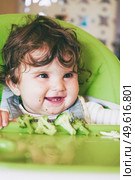 Baby eating food in her green highchair. Стоковое фото, агентство Ingram Publishing / Фотобанк Лори