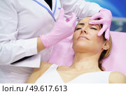Aesthetic doctor injecting botulinum toxin into the forehead of her middle-aged patient. Facial treatment done in a cosmetic surgery clinic.. Aesthetic doctor injecting botulinum toxin into the forehead of her middle-aged patient. Стоковое фото, агентство Ingram Publishing / Фотобанк Лори