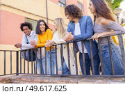 Multi-ethnic group of friends gathered in the street leaning on a railing. Young people having fun together.. Multi-ethnic group of friends gathered in the street leaning on a railing. Стоковое фото, агентство Ingram Publishing / Фотобанк Лори