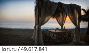 Romantic table setting under canopy on beach overlooking the Mediterranean sea with view of sunset. Стоковое фото, агентство Ingram Publishing / Фотобанк Лори