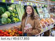 Young female shopper selects and buys tomatoes in supermarket. Стоковое фото, фотограф Яков Филимонов / Фотобанк Лори