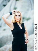 blonde girl in a black trouser suit with blue eyes on the background of a granite quarry from gray rubble. Стоковое фото, агентство Ingram Publishing / Фотобанк Лори
