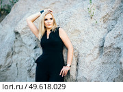 blonde girl in a black trouser suit with blue eyes on the background of a granite quarry from gray rubble. Стоковое фото, агентство Ingram Publishing / Фотобанк Лори