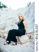 blonde girl in a black trouser suit with blue eyes on the background of a granite quarry from gray rubble. Стоковое фото, агентство Ingram Publishing / Фотобанк Лори