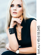 blonde girl in a black trouser suit with blue eyes on the background of a granite quarry from gray rubble. Стоковое фото, агентство Ingram Publishing / Фотобанк Лори
