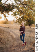 blonde with pigtails in a shirt, jeans, red shoes smiling at sunset. Стоковое фото, агентство Ingram Publishing / Фотобанк Лори