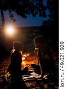 Young couple a guy and a girl in bright knitted hats stopped at a camping near the fire. Стоковое фото, агентство Ingram Publishing / Фотобанк Лори