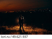 Young couple a guy and a girl in bright knitted hats stopped at a camping near the fire. Стоковое фото, агентство Ingram Publishing / Фотобанк Лори