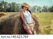 girl with black hair in beige wool coats and suspenders stands near the haystacks. Стоковое фото, агентство Ingram Publishing / Фотобанк Лори