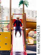 Joyful Girl Slides Down Colorful Playground Slide on a Bright Day in the City. Стоковое фото, фотограф Aleksandr Golubev / Фотобанк Лори