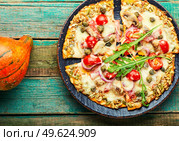 Pizza with salami, cheese, tomato on a pumpkin flatbread. Autumn recipe. Tasty pumpkin-based pizza. Стоковое фото, агентство Ingram Publishing / Фотобанк Лори