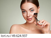 Close up of a beautiful young woman curling her eyelashes. Eyelash extensions. Стоковое фото, агентство Ingram Publishing / Фотобанк Лори