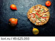 Pizza with salami, cheese, tomato on a pumpkin flatbread. Autumn recipe. Tasty pumpkin-based pizza. Стоковое фото, агентство Ingram Publishing / Фотобанк Лори