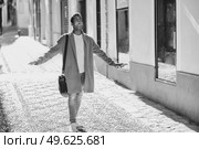 Young black man walking down the street carrying a briefcase and a smartphone. Cuban guy in urban background.. Young black man walking down the street carrying a briefcase and a smartphone. Стоковое фото, агентство Ingram Publishing / Фотобанк Лори