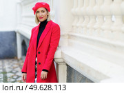 Beautiful middle-aged woman wearing red winter clothes posing looking at camera leaning against a wall. Female wearing coat, skirt and beret outdoors.. Beautiful middle-aged woman wearing red winter clothes posing looking at camera. Стоковое фото, агентство Ingram Publishing / Фотобанк Лори