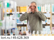 Senior man with headache looking for medicine in pharmacy. Стоковое фото, фотограф Яков Филимонов / Фотобанк Лори