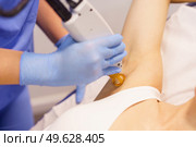 Woman receiving underarm laser hair removal at a beauty center. Laser depilation treatment in an aesthetic clinic.. Woman receiving underarm laser hair removal at a beauty center. Стоковое фото, агентство Ingram Publishing / Фотобанк Лори