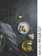 Capers on white plate at dark concrete kitchen table with olive oil, garlic, cutlery and table cloth. Mediterranean food appetizer. Pickled Italian food. Top view with copy space. Стоковое фото, агентство Ingram Publishing / Фотобанк Лори