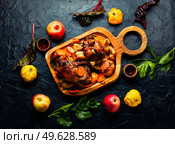 Pork knuckle stewed with quince and apples on cutting board. Pork shank baked with apples. Стоковое фото, агентство Ingram Publishing / Фотобанк Лори